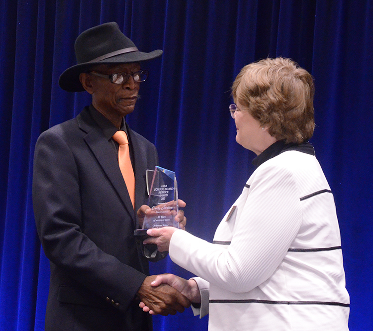 Man in hat with suit and woman holding trophy